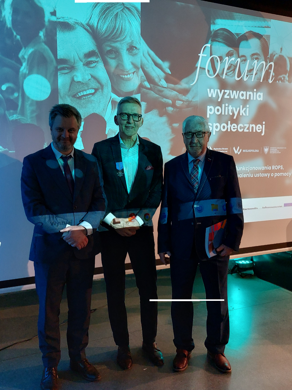 Trzech mężczyzn w garniturach na tle slajdu FORUM – Wyzwania polityki społecznej
Prof. Jerzy Babiak UAM Poznań
Prof. Mirosław Grewiński – Rektor Uczelni Korczaka w Warszawie
Dyrektor PCPR w Krotoszynie Andrzej Piotrowski

