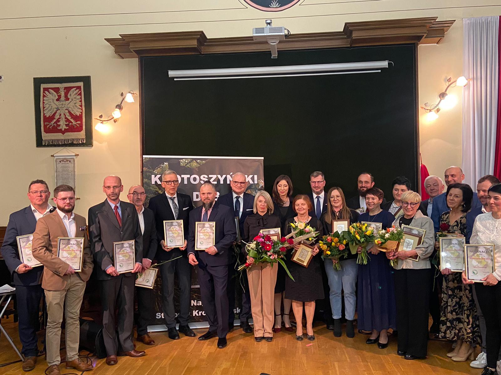 Grupa osób na scenie z dyplomami i kwiatami, laureaci konkursu Starosty Krotoszyńskiego "Krotoszyński Dąb 2023